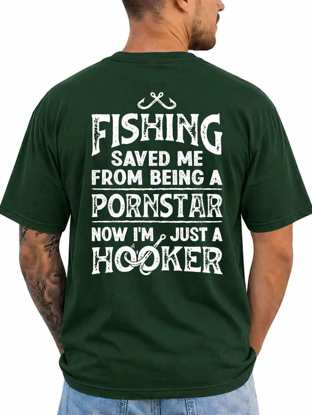 A man wearing a dark green t-shirt, viewed from the back. The shirt features a large white graphic text print that reads 'FISHING SAVED ME FROM BEING A PORNSTAR NOW I'M JUST A HOOKER' with a fishing hook and line design.