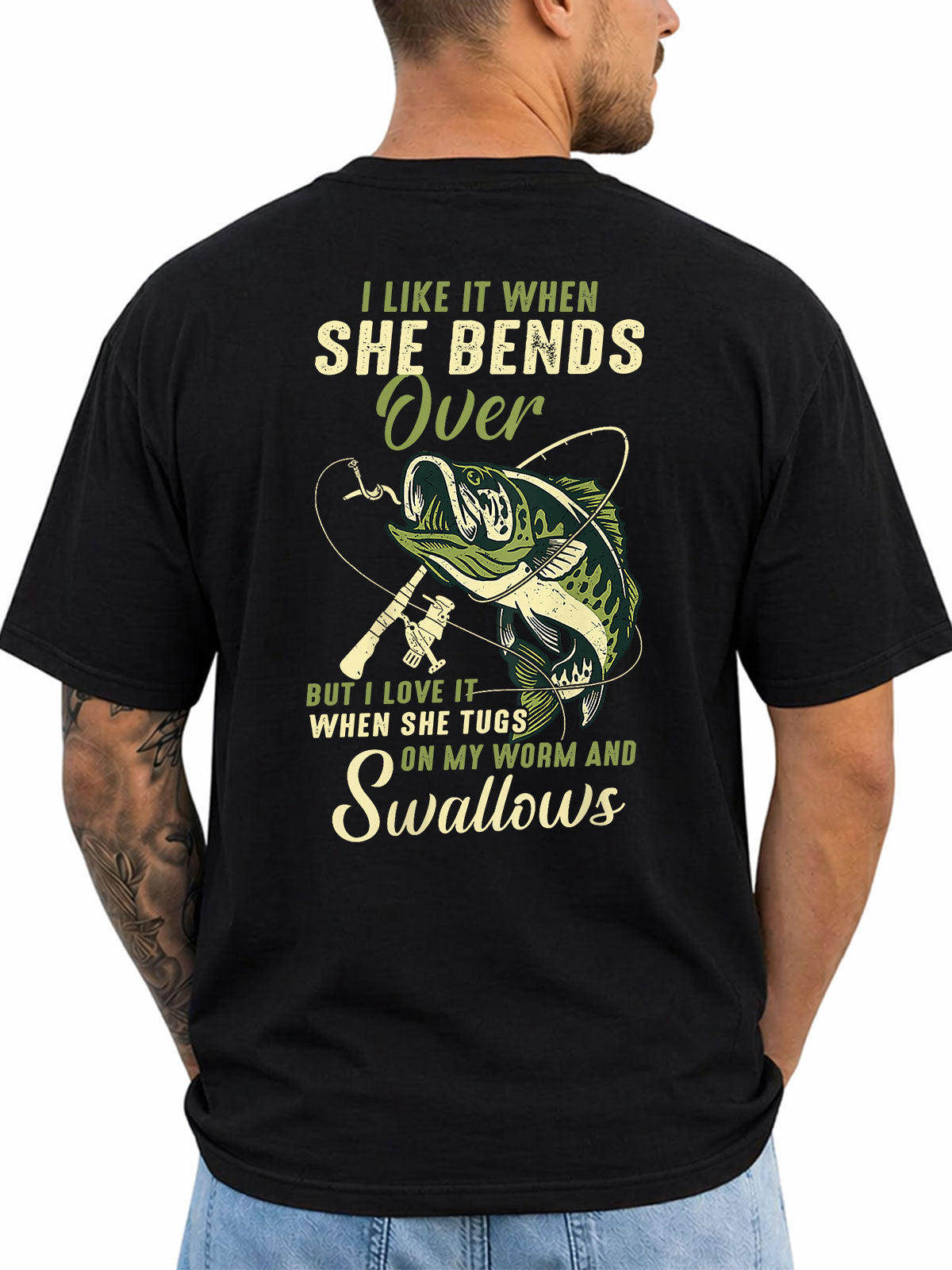 Black T-shirt back with bass, rod, lure, and explicit fishing-innuendo graphic reading 'I LIKE IT WHEN SHE BENDS OVER BUT I LOVE IT WHEN SHE TUGS ON MY WORM AND SWALLOWS'