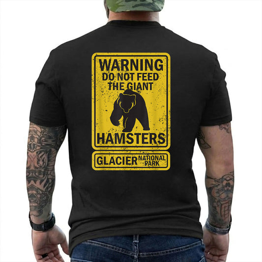Black T-shirt back with yellow warning sign with a bear silhouette and giant hamsters joke reading 'WARNING DO NOT FEED THE GIANT HAMSTERS GLACIER NATIONAL PARK'