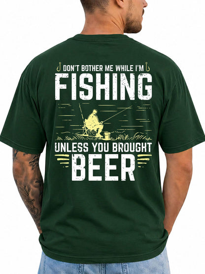 Forest green T-shirt back with seated angler and bold fishing slogan artwork