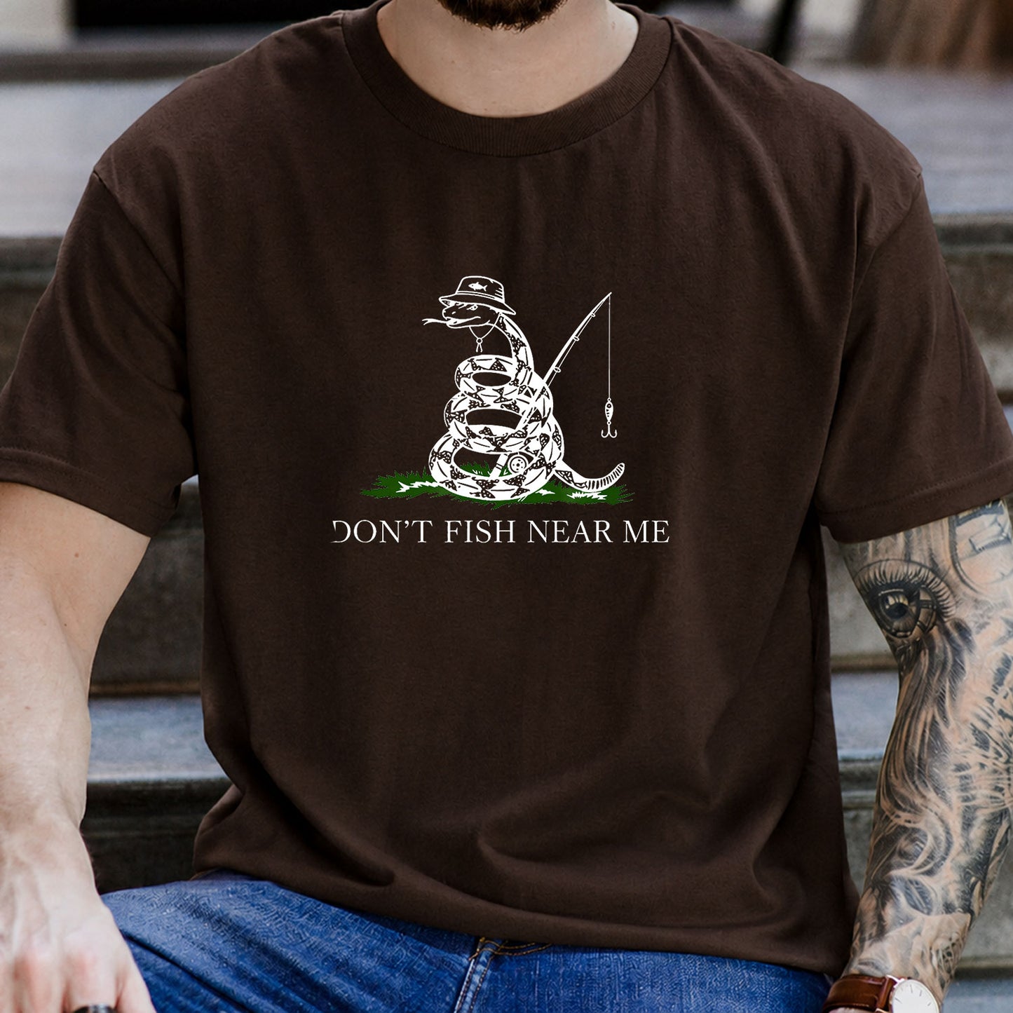 Forest Green T-shirt front with coiled snake angler holding a fishing rod and lure