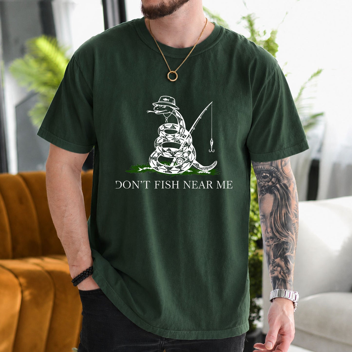 Military Green T-shirt front with coiled snake angler holding a fishing rod and lure